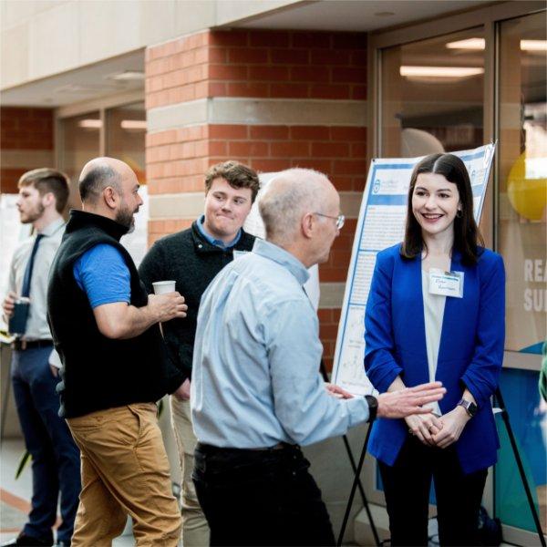 Students discuss their research with faculty members during Student Scholars Day