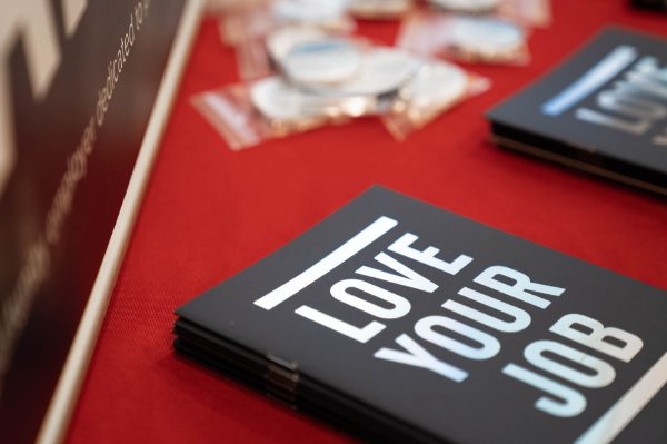notebooks that read Love Your Job on a red tablecloth, pins in plastic near the top