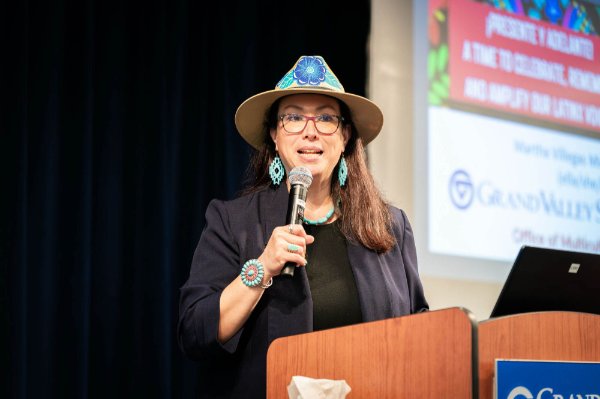 Martha Villegas Miranda wears a hat at the podium