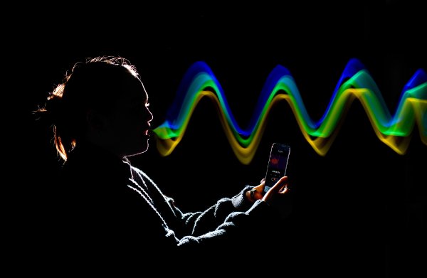A photo illustration of colorful "sound waves" coming from a person's mouth while holding a cell phone.