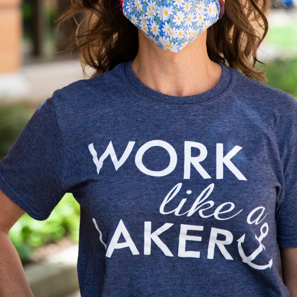 A woman wearing a blue "Work like a Laker" t-shirt and face covering.