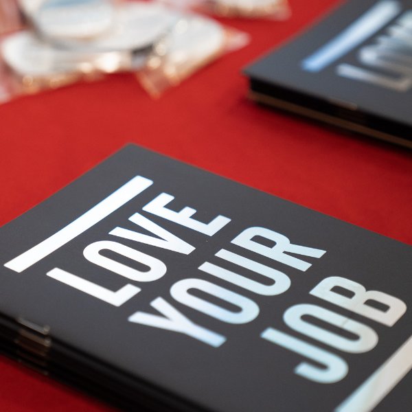 A notebook on a table that reads "Love Your Job"