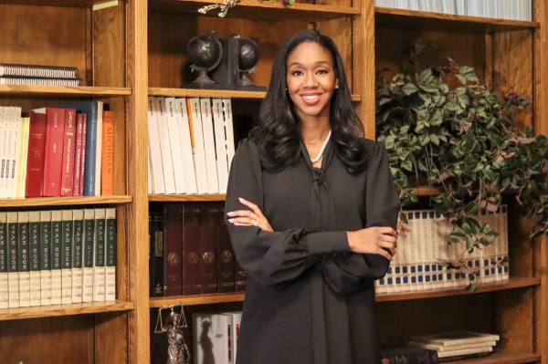 Krya Harris Bolden stand with arms crossed in front of a bookcase