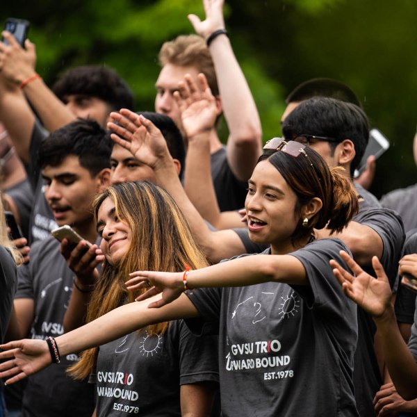 High school students from TRIO Upward Bound sing a song and perform gestures with open arms