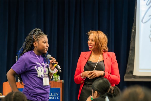 Erica Robertson stands next to a student as she answers a question into a microphone.