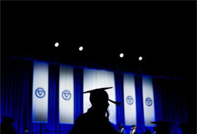 A silhouetted graduate walks in front of the stage during Commencement ceremonies.
