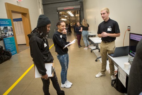 A presenter talks about his project with prospective students.