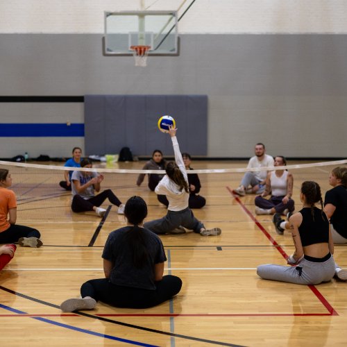 Students participating in seated volleyball at an adaptive intramural sports event.