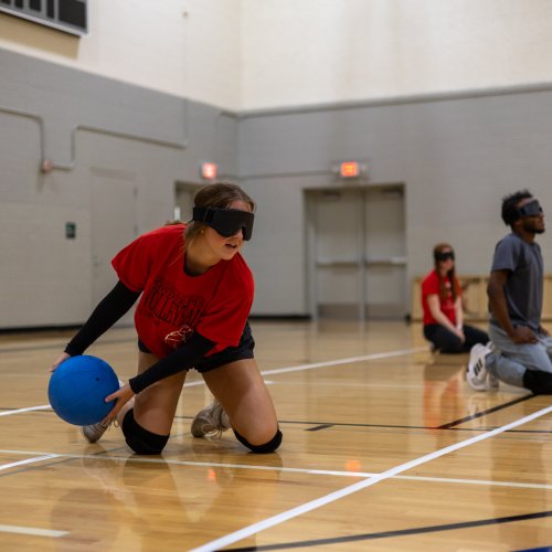 Student participating in goalball at an adaptive intramural sports event.