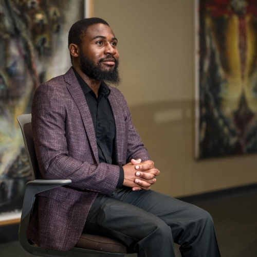 Kyezie Bwanangela seated for portrait in maroon suit jacket