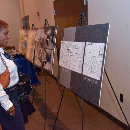 woman stands to look at poster boards of renderings for the new Battle Creek Innovation Hub