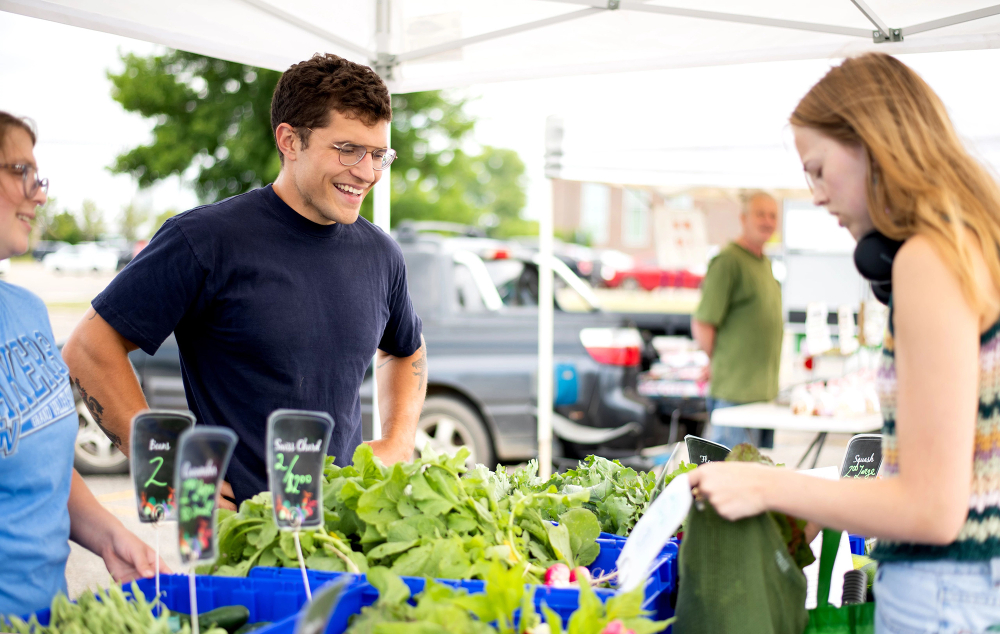 one customer looking at produce at the farmers market under a canopy