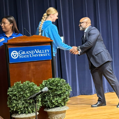 VP Truss shakes the hand of a high school student as she accepts a certificate; person behind podium hands certificate to next person in line