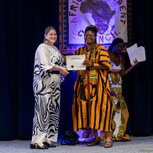 two people each holding a certificate and dressed in traditional African outfits