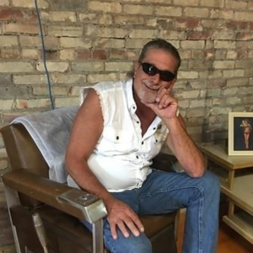 Jerry Bosch seated in chair against brick wall