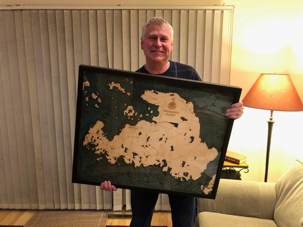 Tony Nieuwkoop holds a framed map of Drummond Island