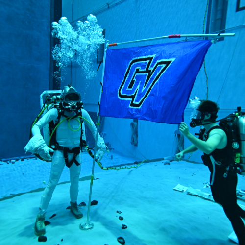 underwater photo in pool, scuba divers hoist a GV flag on a flagpole