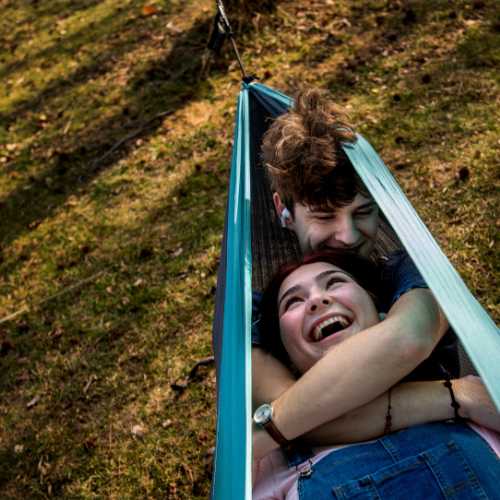two people in a hammock taken from above, brown ground below