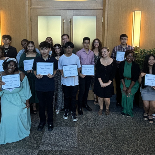 group of students and instructors standing in hallway, students holding certificates