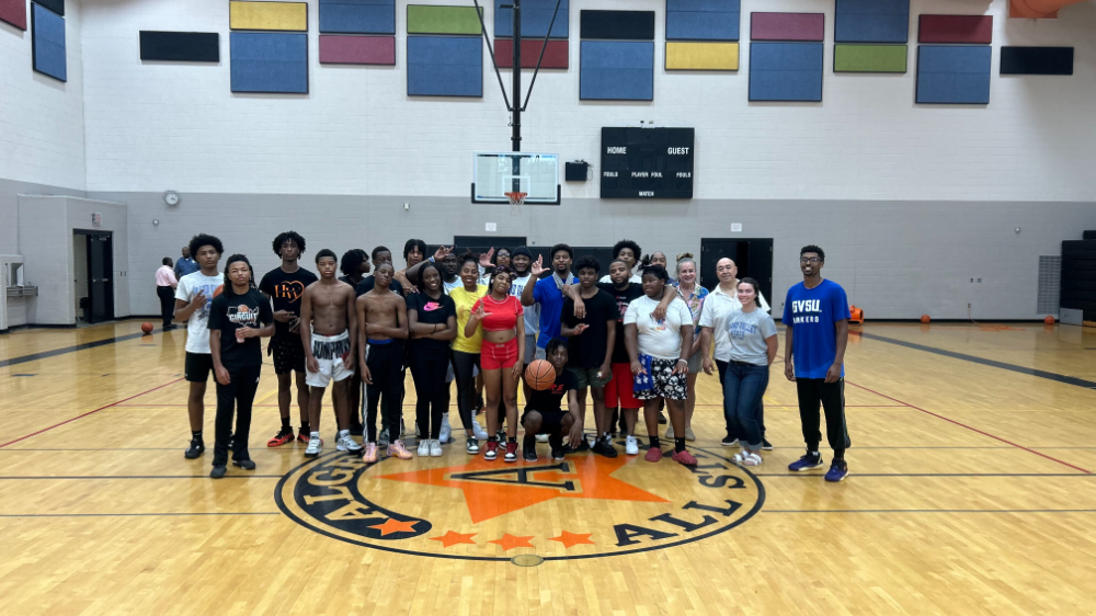 group of students, faculty and staff at the center of a basketball court