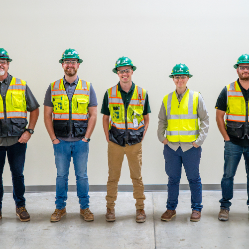 five people in safety vests and hard hats standing in line