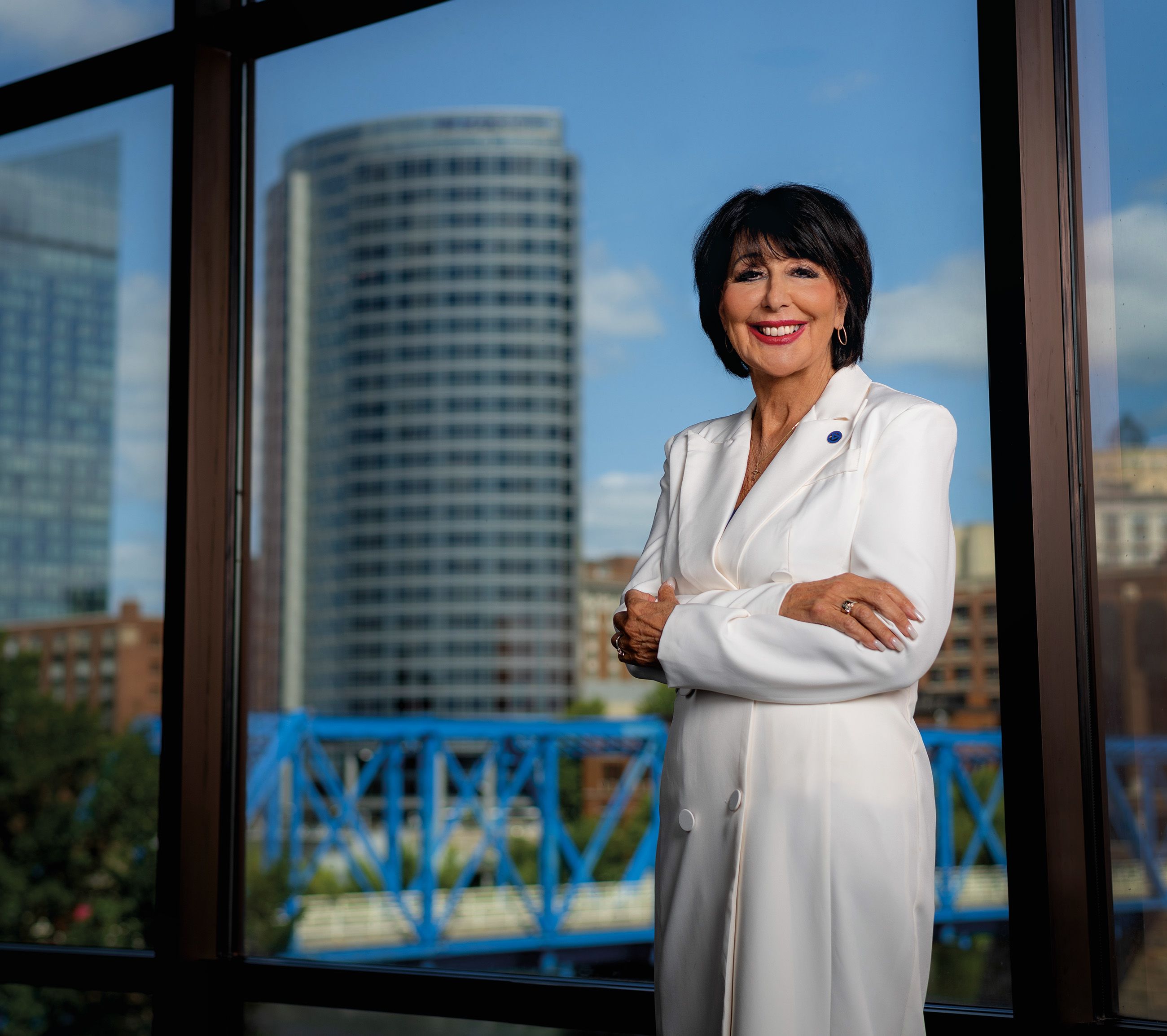 President Mantella in white jacket against window showing skyline of Grand Rapids