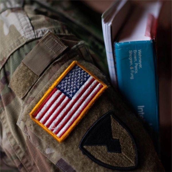 A person with an American flag on their sleeve holds books.