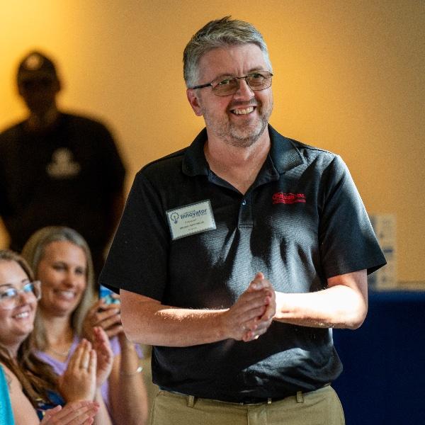 Michael Gerstweiler, owner of Pribusin Inc., reacts near his family, (from left) Nick Gerstweiler, Jessica Gerstweiler and wife, Sue Gerstweiler, after winning the 2024 Lakeshore Innovator of the Year award at the Muskegon Innovation Hub on July 25.