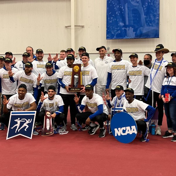 The men's track and field team poses for a photo with the trophy after winning the national championship.