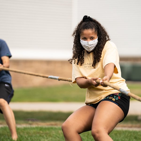 An international student wearing a mask participates in a game of tug of peace.