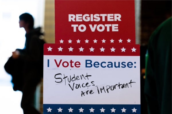 A small poster reads &ldquo;Register to vote&rdquo;. Below, a white space is open to be written in. Printed words read &ldquo;I vote because:&rdquo; and handwritten words below to read &ldquo;student voices are important.&rdquo; 