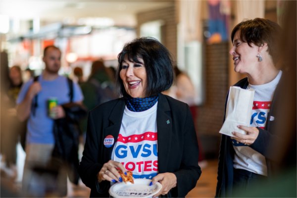 President Philomena V. Mantella, left, and VP for Student Affairs Jenny Hall-Jones, right, laugh and mingle with students who were waiting in line to vote in the midterm elections in the Kirkhof Center Nov. 8. 