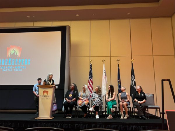 Belinda Bardwell, standing, and Dawn Rutecki, standing behind Bardwell, are on stage during an event in Battle Creek that celebrated all Native American Heritage Fund grant recipients.