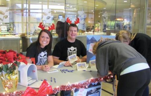 Students signing holiday cards by Fresh Food Co.