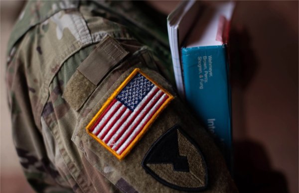 A person with an American flag on their sleeve holds books.