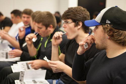 Football players swab their cheeks as part of the registry process to be a bone marrow donor.