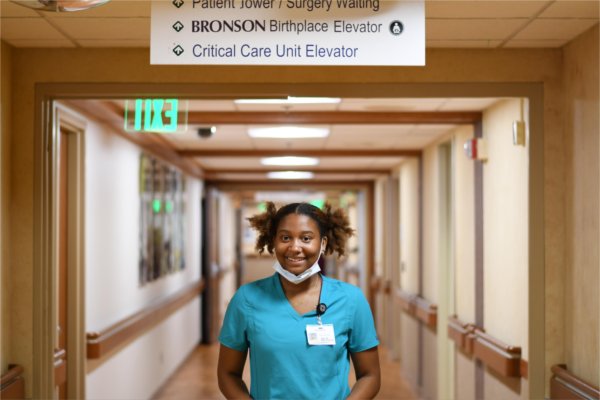 Mariah Rudolph in blue scrubs standing in hospital hallway