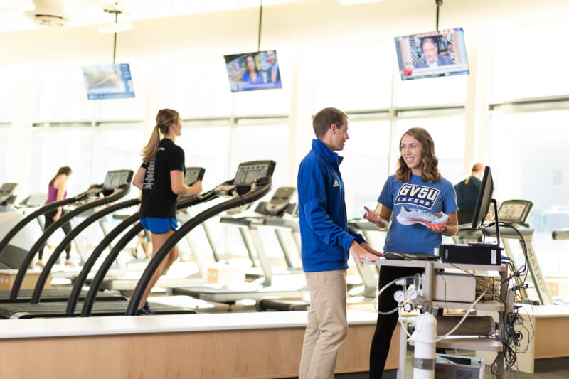 two people talking while one person runs on a treadmill in the Rec Center