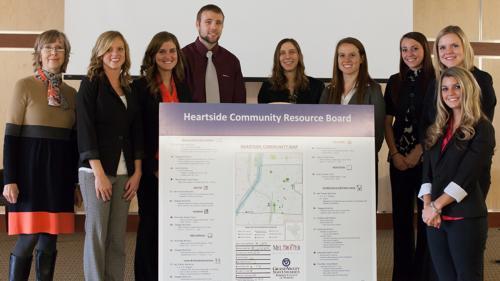 Students from the Kirkhof College of Nursing are pictured with a resource board they created for Mel Trotter Ministries. The poster indicates Heartside resources. At left is Nancy Schoofs, associate professor of nursing.