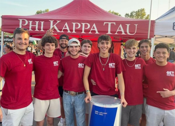 fraternity members in red shirt stand in front of a Phi Kappa Tau red tent