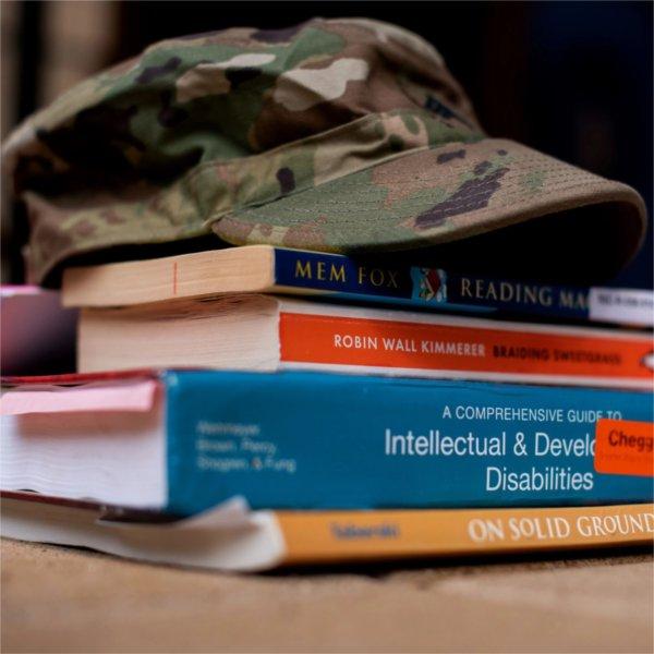 camouflage hat with brim atop a stack of books