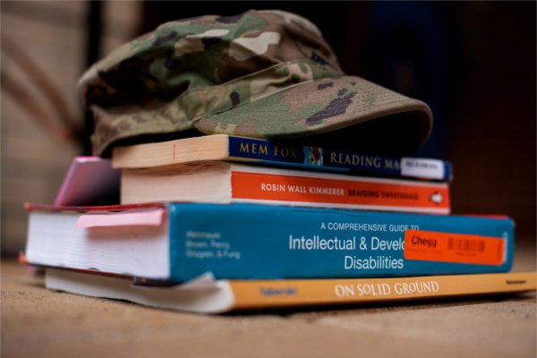 camouflage hat with brim atop a stack of books