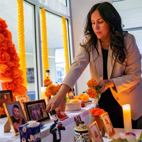 Thalia Guerra-Flores places flowers at the Día de Muertos (Day of the Dead) altar in the Office of Multicultural Affairs.