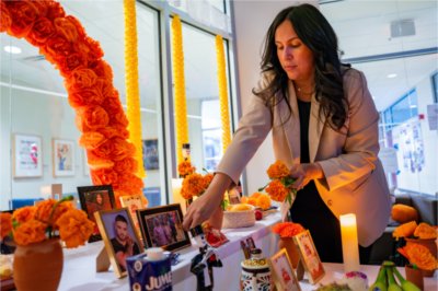 Thalia Guerra-Flores places flowers at the Día de Muertos (Day of the Dead) altar in the Office of Multicultural Affairs.