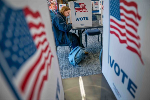  A student votes near pictures of American flags.