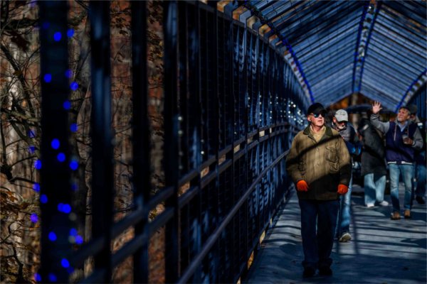 A group of people cross a blue bridge on a campus tour. 