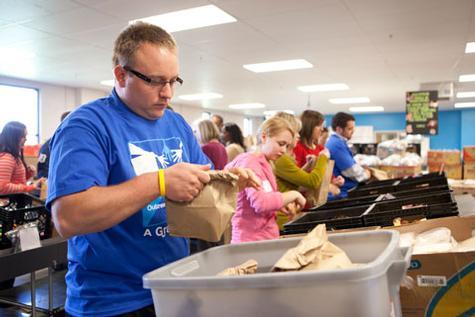 Alumni volunteers pack sack suppers at Kids' Food Basket, one of the activities planned during COW.