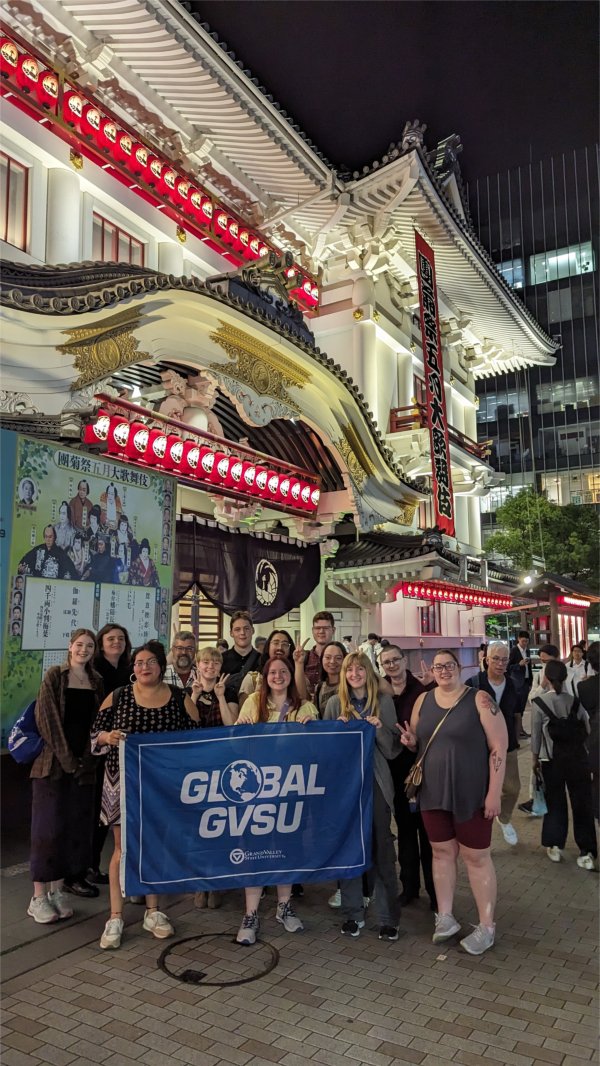 group holding Global GVSU blue flag in front of Japanese theater