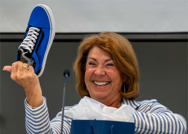  A person shows off a big smile as they hold up a blue sneaker.