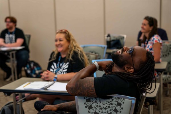  A person leans back and laughs during a discussion. 